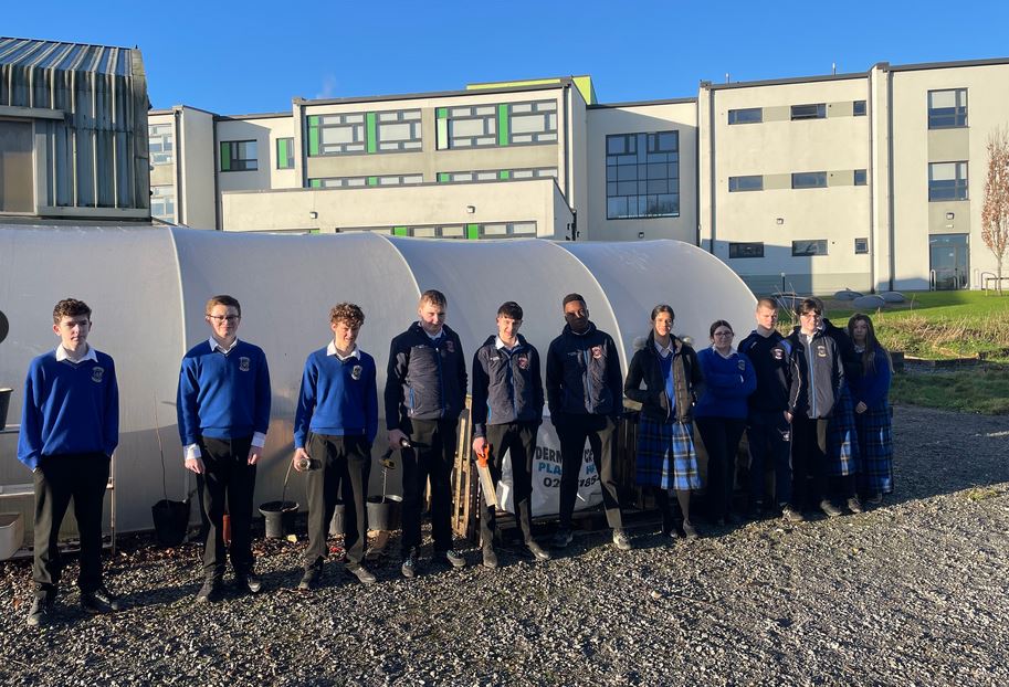 Studetns pictured outside polytunnel. School in background.