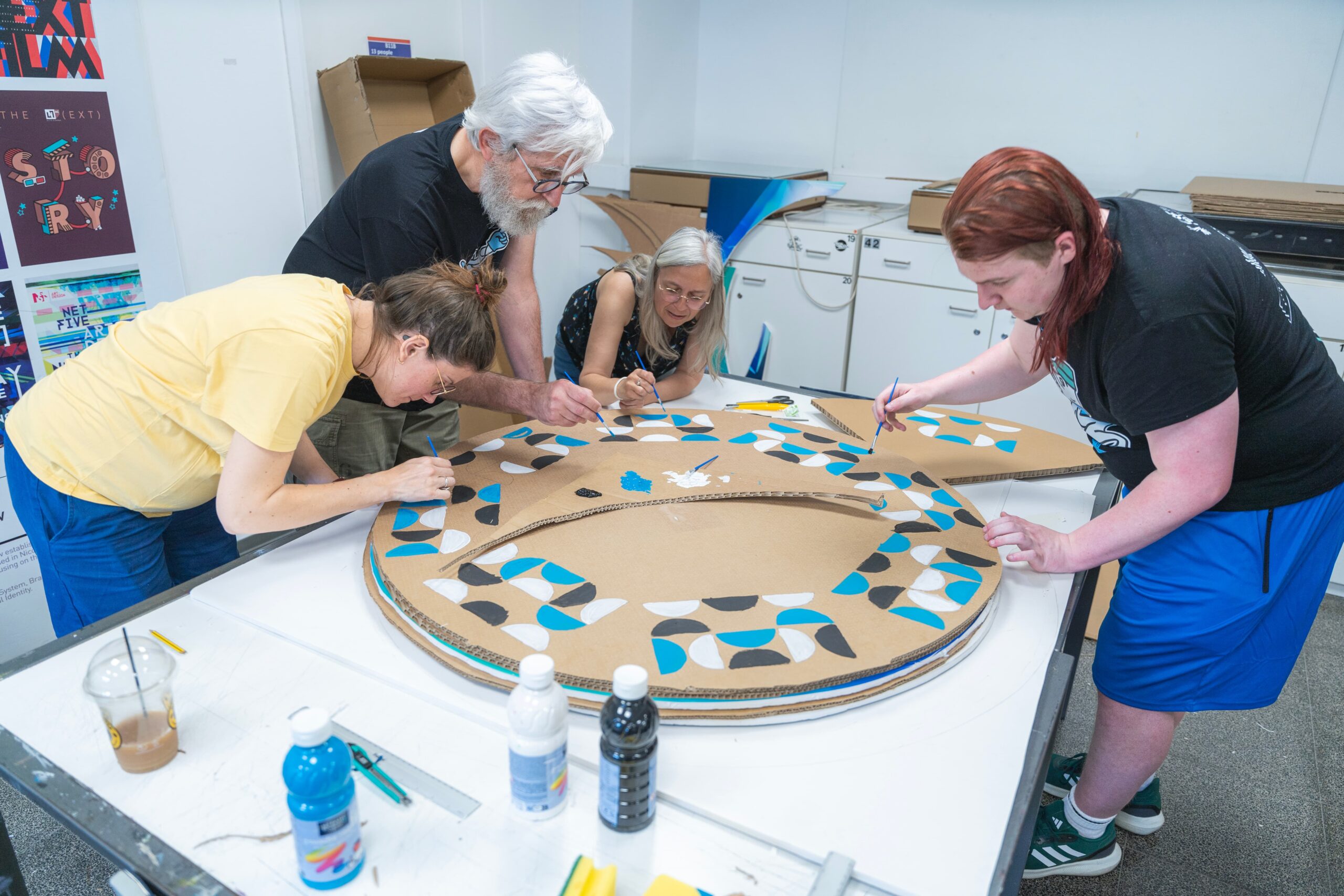 Students participating in a design workshop. Cardboard and paint in the photo,