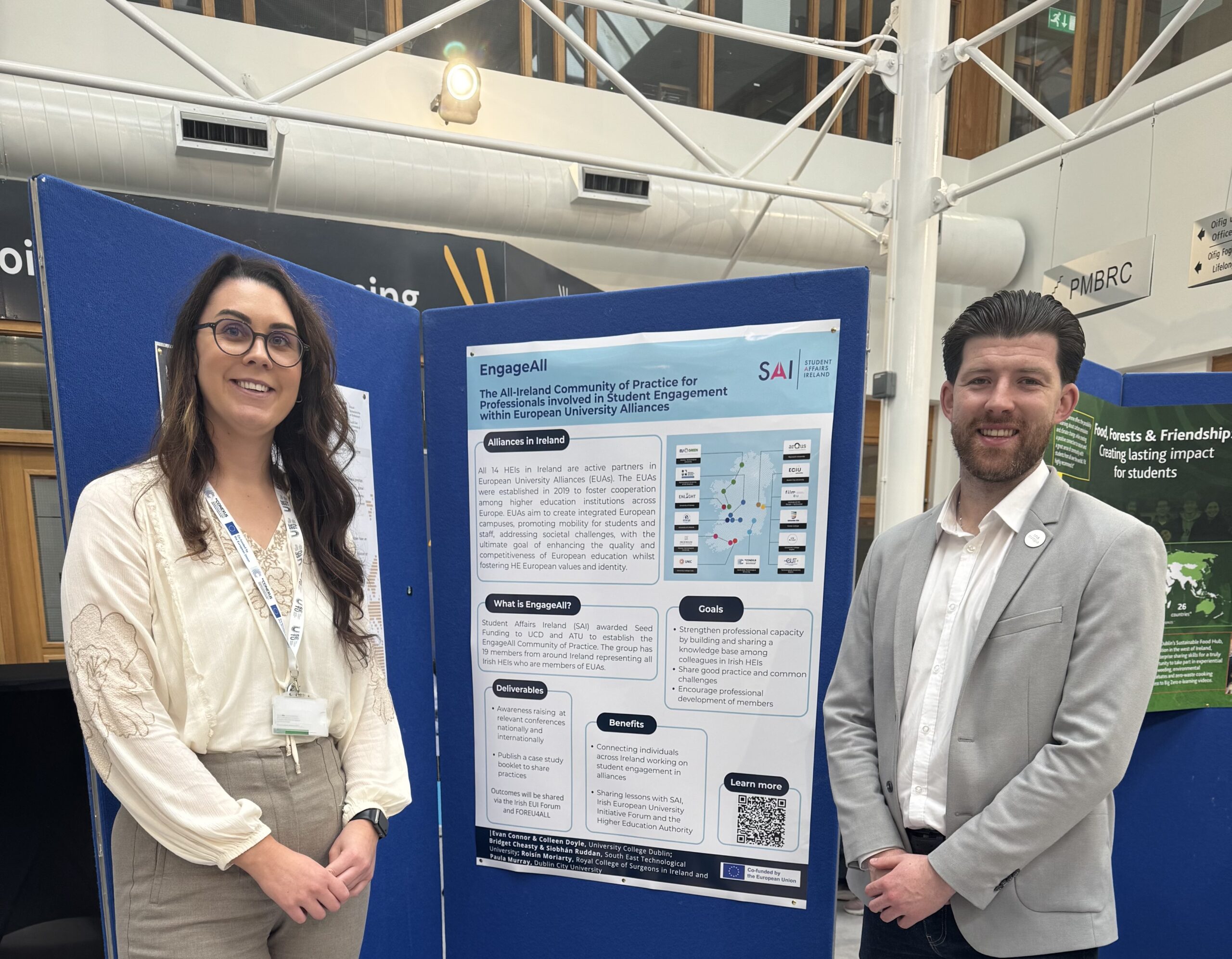 Two people standing in front of a poster 