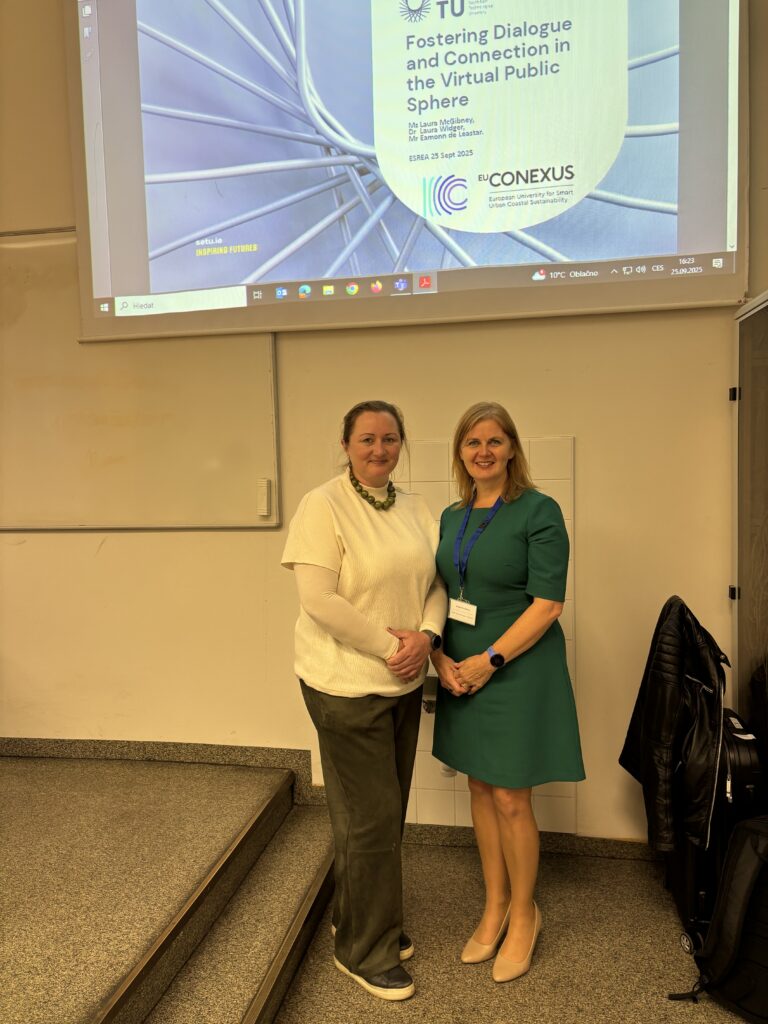 Two ladies standing up in front of a presentation screen